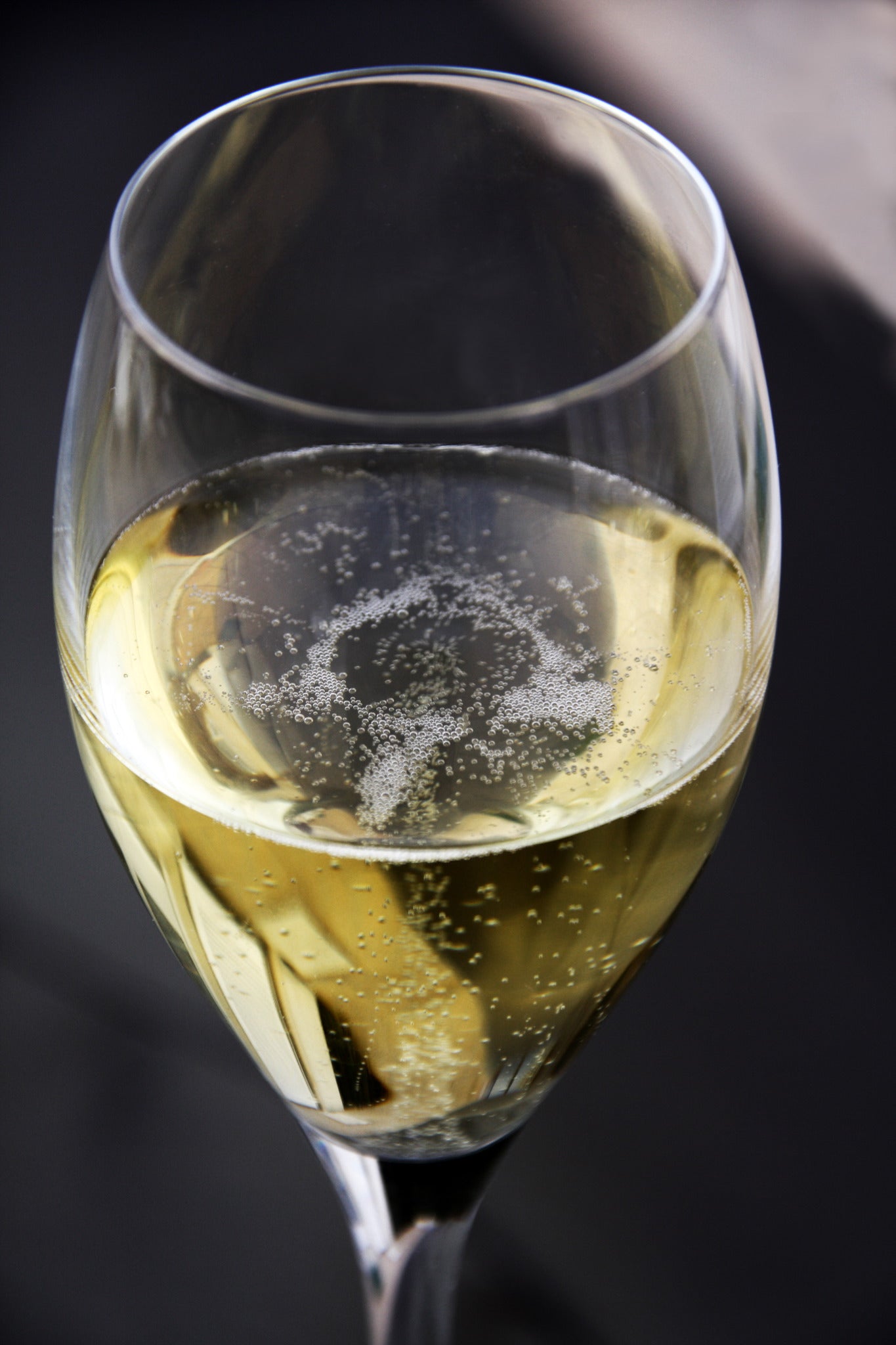A coupe glass of Champagne against a dark background